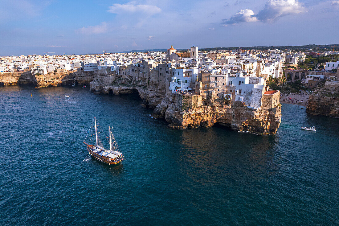 Segelboot vor Anker im Wasser vor dem weißen Dorf Polignano a Mare bei Sonnenuntergang, Provinz Bari, Adria, Mittelmeer, Apulien, Italien, Europa