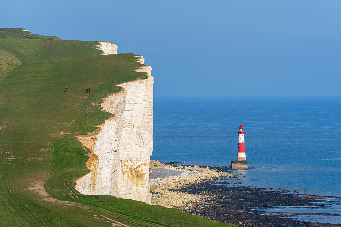 View of the coast of the Seven Sisters white chalk cliffs with the Beachy Head lighthouse in the background, South Downs National Park, East Sussex, England, United Kingdom, Europe