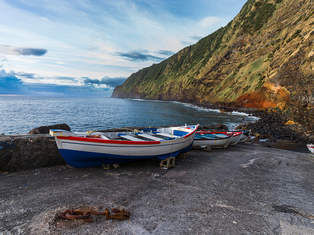 Einige Boote auf einem Steg unterhalb einer Klippe auf der Insel Sao Miguel auf den Azoren, Portugal, Atlantik, Europa