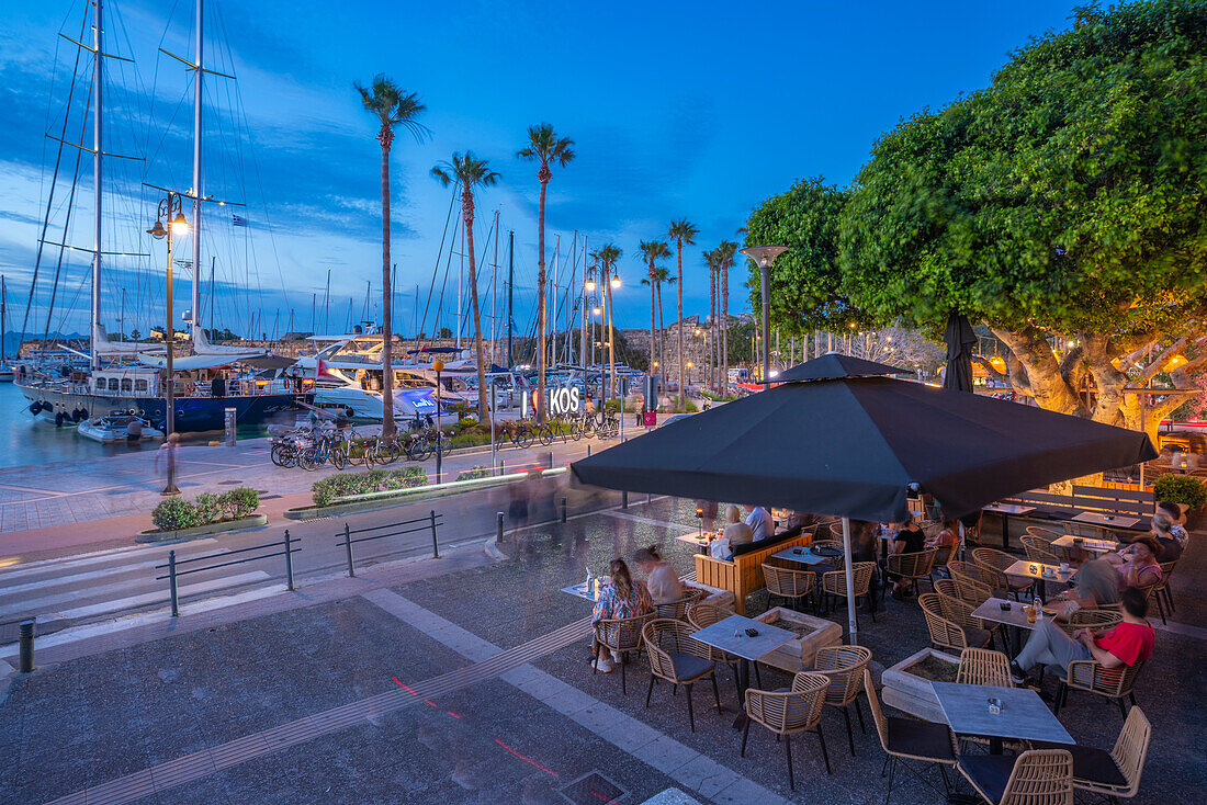 Blick auf Cafés und Boote im Hafen von Kos in der Abenddämmerung, Kos Stadt, Kos, Dodekanes, Griechische Inseln, Griechenland, Europa