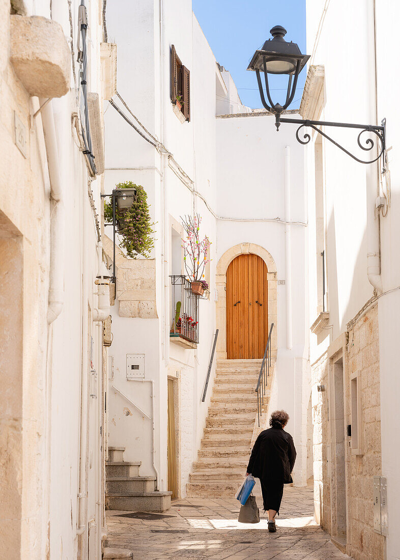 Frau geht in einer engen Gasse in der Altstadt, Locorotondu, Apulien, Italien, Europa