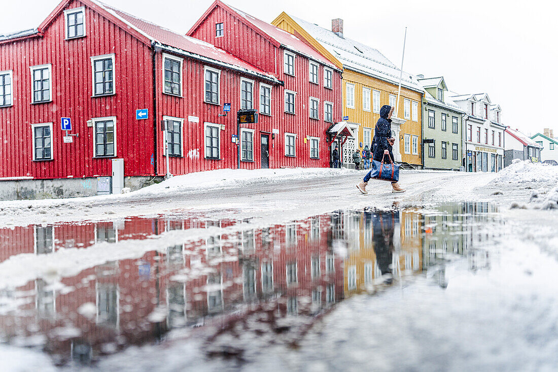 Tourist beim Spaziergang in der Nähe der bunten Häuser von Tromso im Winter, Tromso, Norwegen, Skandinavien, Europa