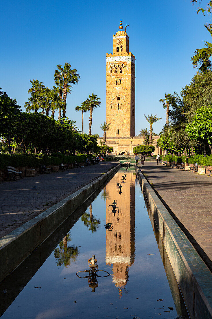 Antiker Minarett-Turm der Koutoubia-Moschee, UNESCO-Weltkulturerbe, spiegelt sich im Wasser in einem palmengesäumten Park, Marrakesch, Marokko, Nordafrika, Afrika