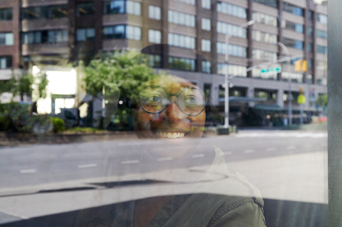 USA, New York, New York City, Smiling woman reflected in window in city