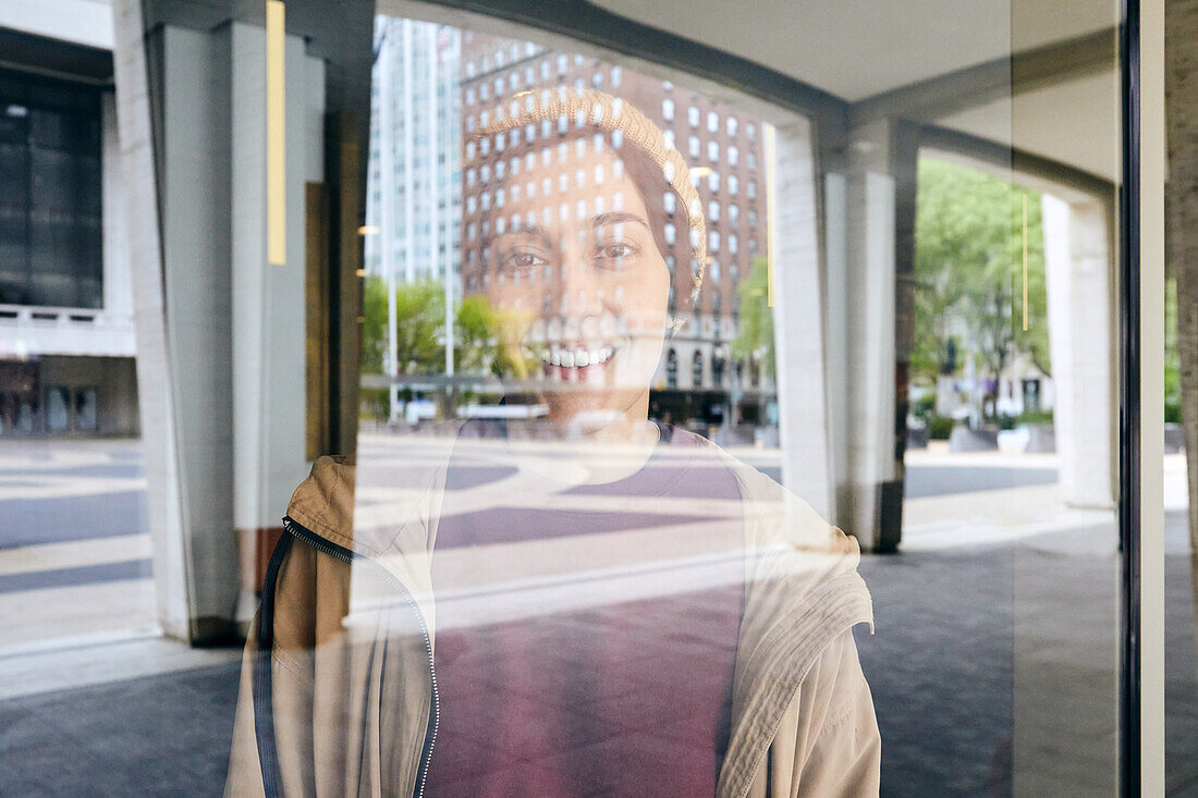 Porträt einer lächelnden Frau durch ein Fenster in der Stadt gesehen