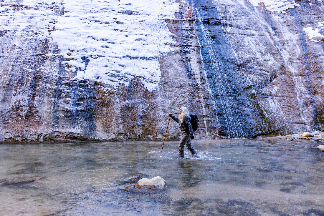 USA, Utah, Springdale, Zion National Park, Senior woman crossing river while hiking in mountains