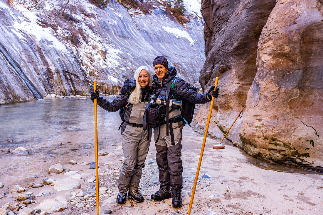 USA, Utah, Springdale, Zion National Park, Älteres Paar überquert Fluss beim Wandern in den Bergen