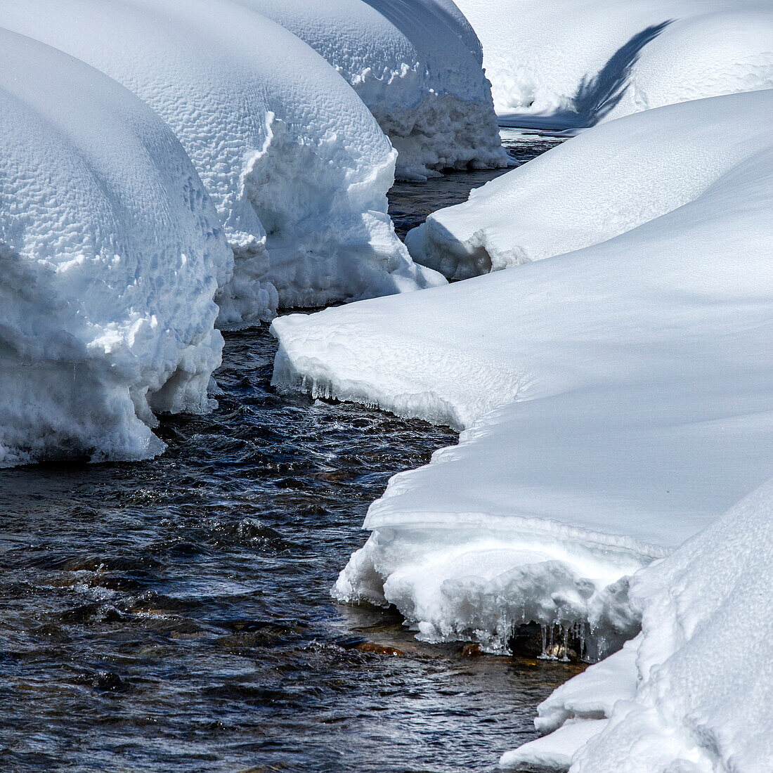 Waldbach mit Schnee an den Ufern