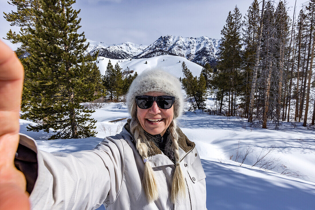 USA, Idaho, Sun Valley, Ältere Frau macht Selfie in verschneiten Bergen