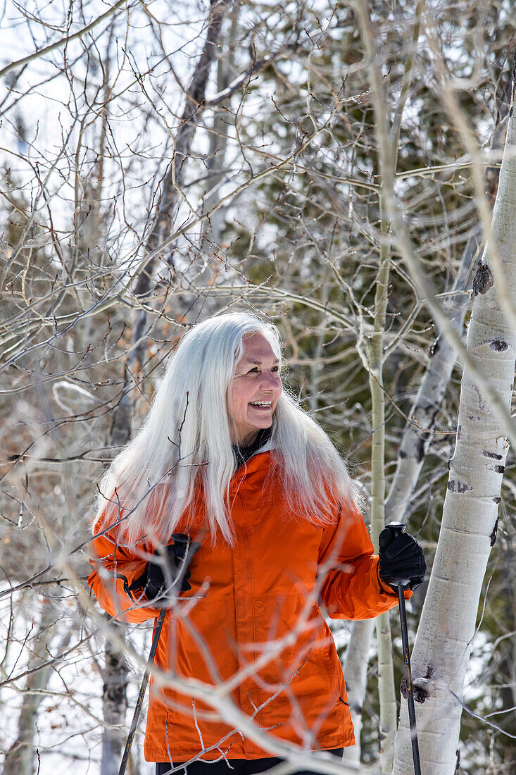 Smiling senior woman snowshoeing in nature 