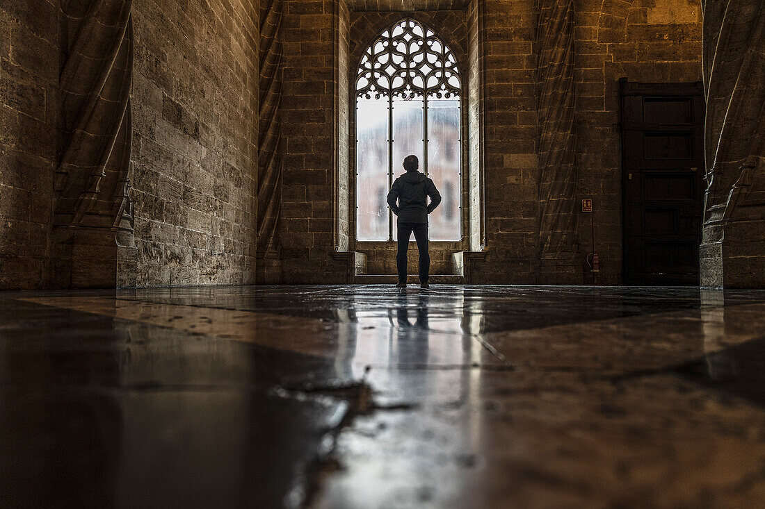 Spain, Valencia, Rear view of man looking through window in old empty church