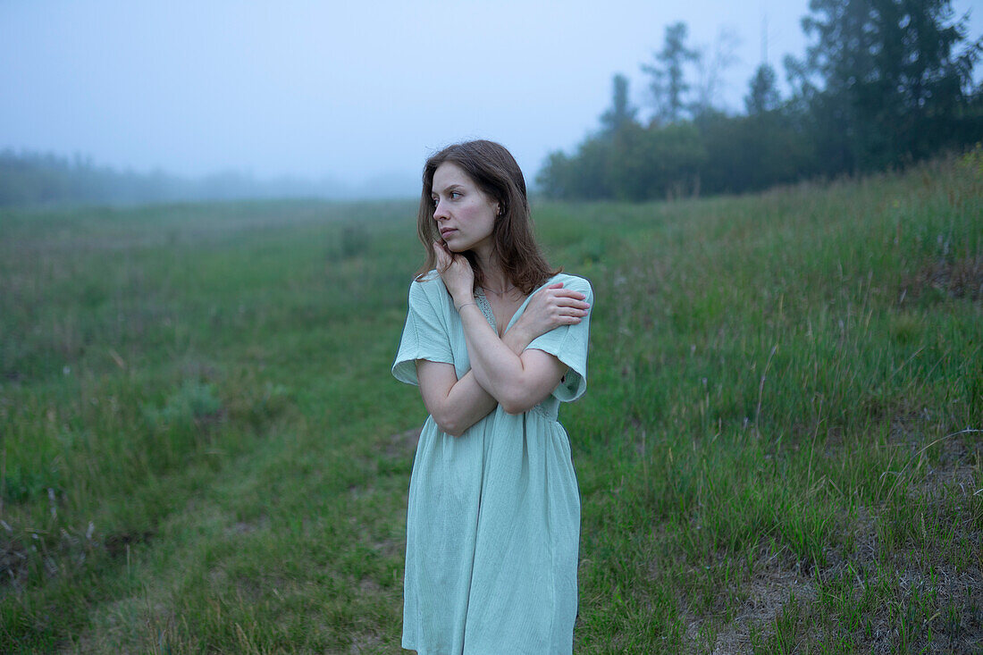 Woman standing in meadow on foggy day
