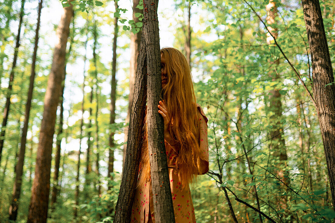 Junge Frau berührt Baum im Wald