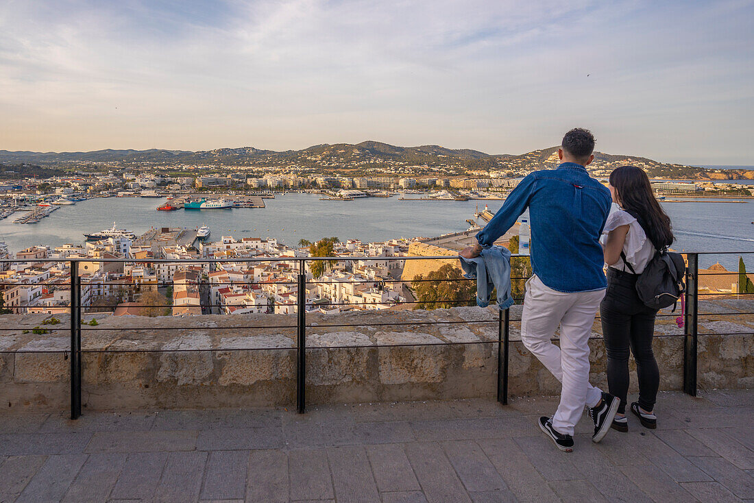 Paar mit Blick auf den Hafen, den Stadtteil Dalt Vila und die Stadtmauer, UNESCO-Weltkulturerbe, Ibiza-Stadt, Eivissa, Balearen, Spanien, Mittelmeer, Europa