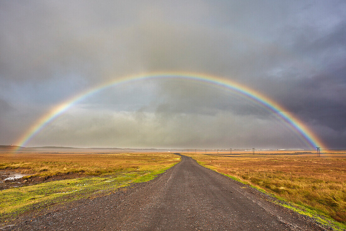 Ein Regenbogen überspannt eine Straße in der Landschaft bei Rif, Halbinsel Snaefellsnes, Westisland, Polargebiete