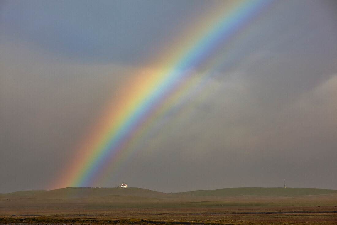Ein Regenbogen wölbt sich über einer Kirche in der Landschaft nahe der Stadt Rif, Halbinsel Snaefellsnes, im Westen Islands, Polarregionen