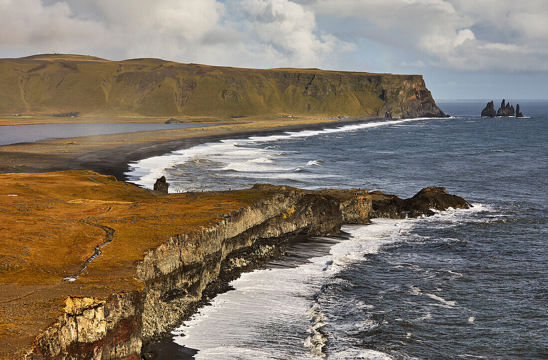 Blick von der Insel Dyrholaey entlang des Strandes Reynisfjara auf die Stadt Vik, Südisland, Polargebiete