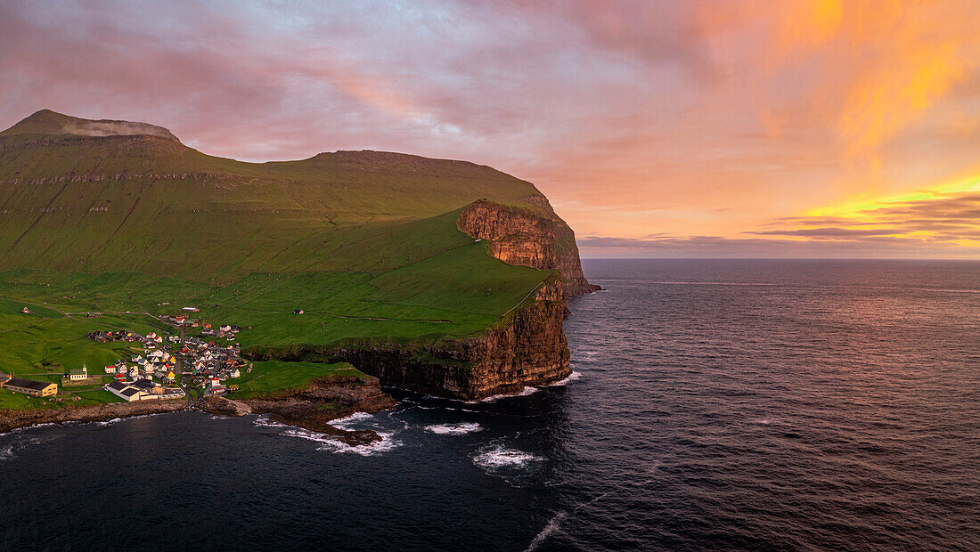 Fiery sky at dawn over the village of Gjogv ovelooking the ocean, aerial view, Eysturoy Island, Faroe Islands, Denmark, Europe