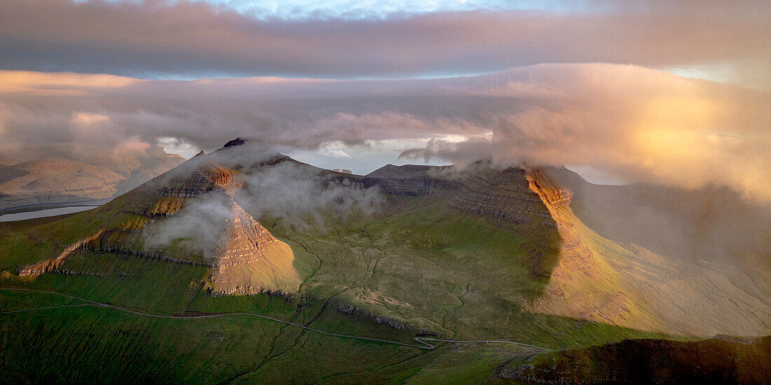 Foggy sunrise over Slaettaratindur peak, highest mountain of Faroe Islands, aerial view, Eysturoy Island, Denmark, Europe