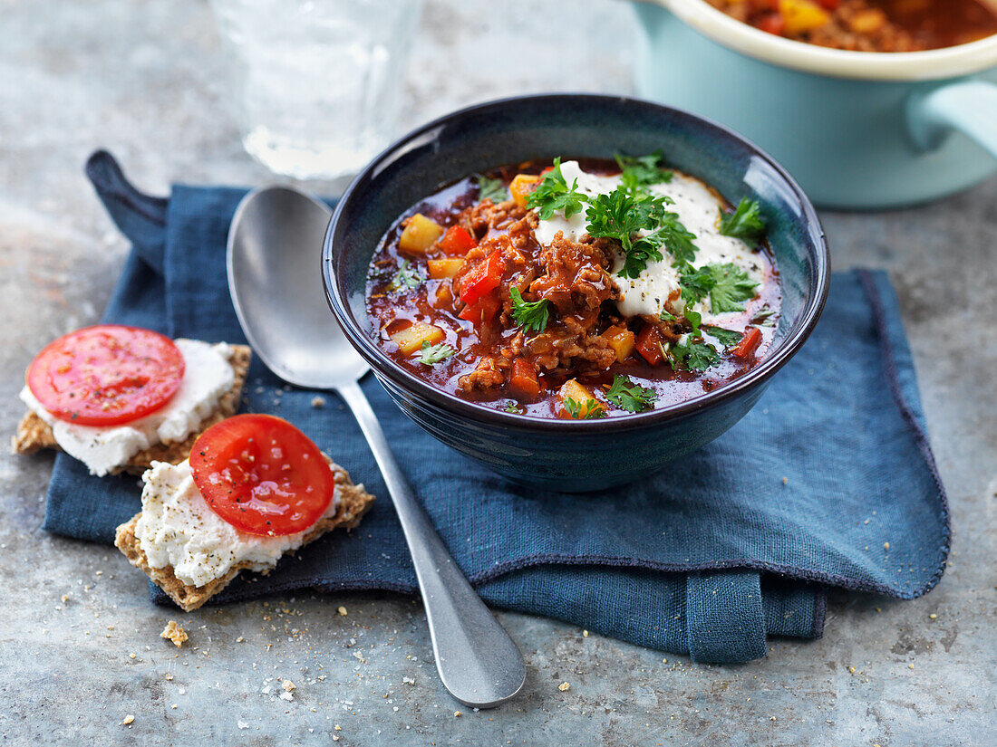 Goulash with yogurt, parsley, and rye bread with cream cheese and tomatoes