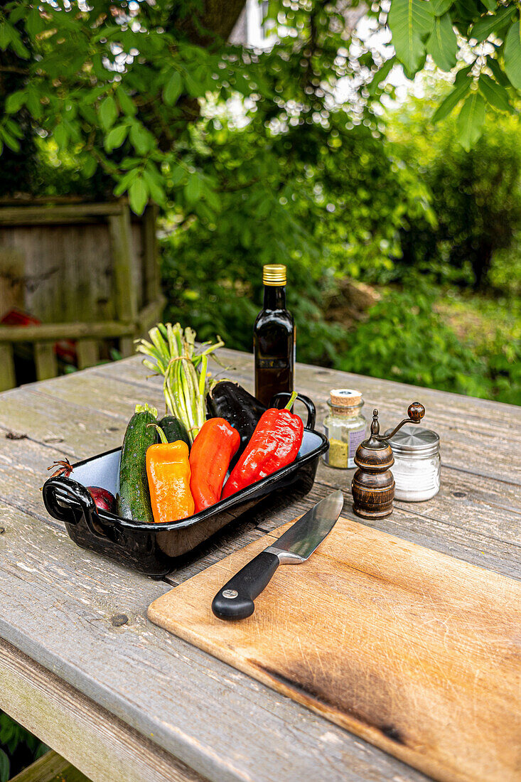 Fresh vegetables, spices, knife, and wooden cutting board on garden table