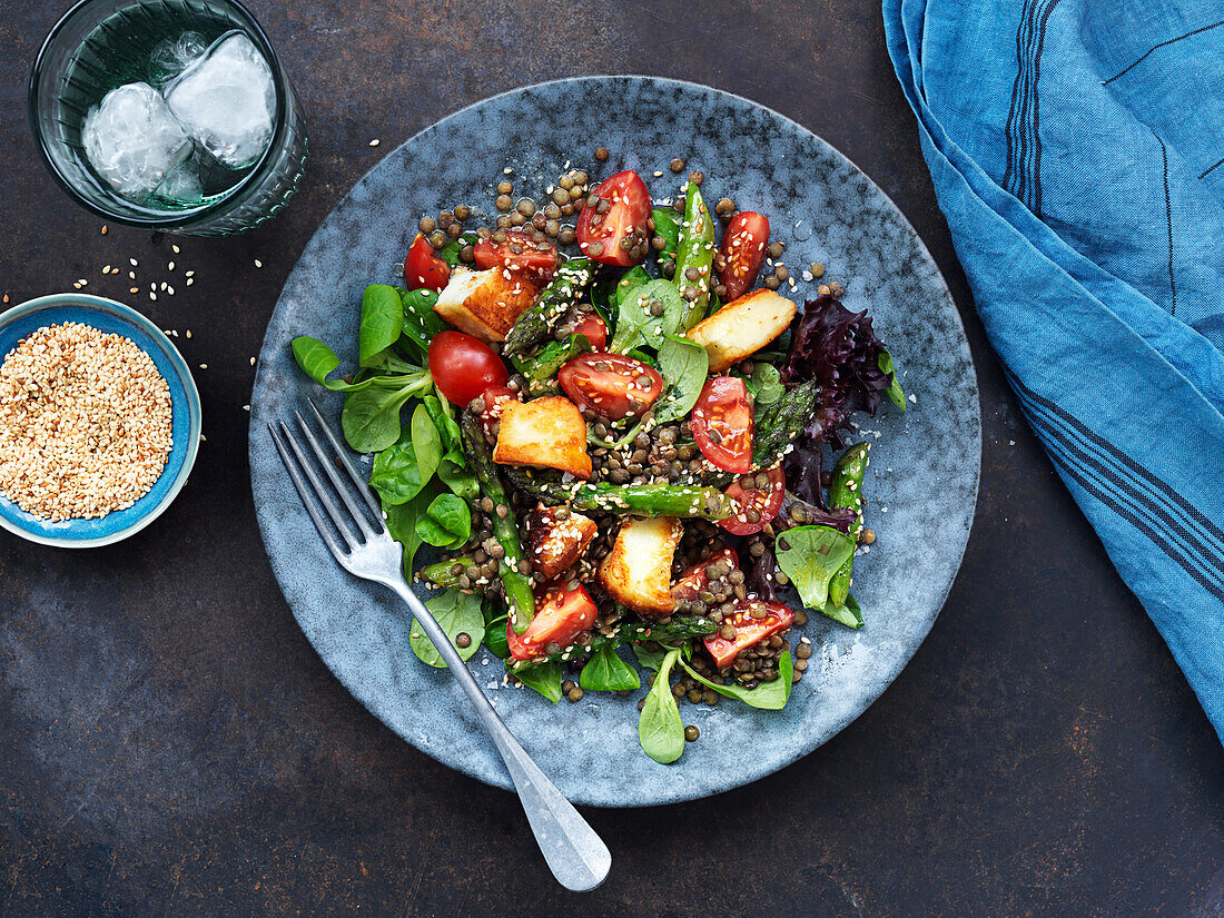 Salad with lentils, spinach, tomatoes, halloumi, and sesame