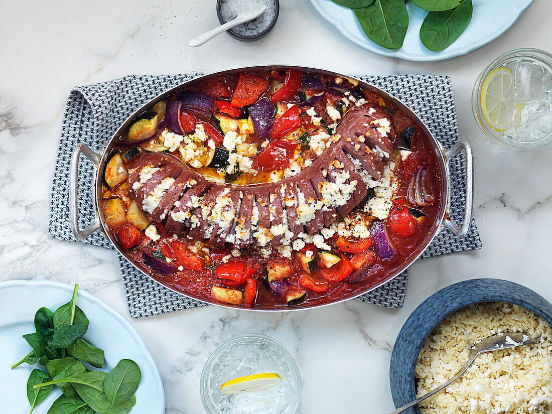 Bratwurst from the oven with vegetables, tomato sauce, and feta