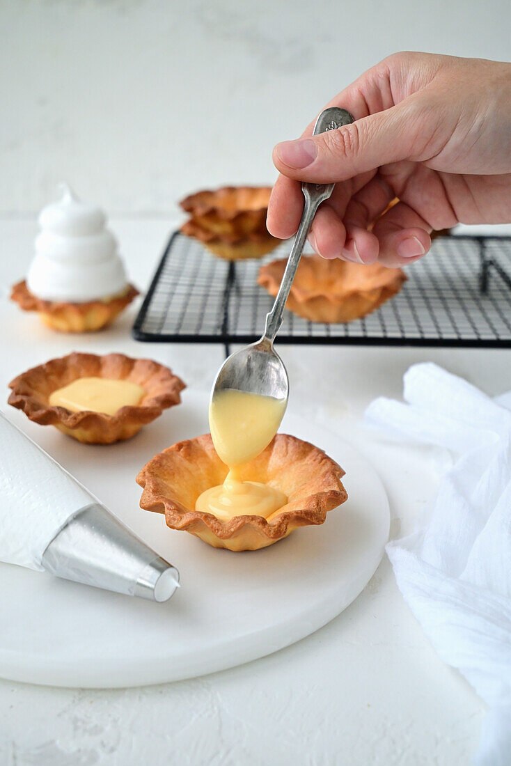 Preparing tartlet with lemon curd and meringue