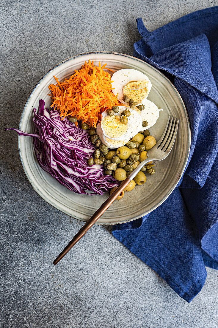 Bowl mit gekochten Eiern, Kapern, Oliven, Rotkohl und Möhren (Keto-Küche)