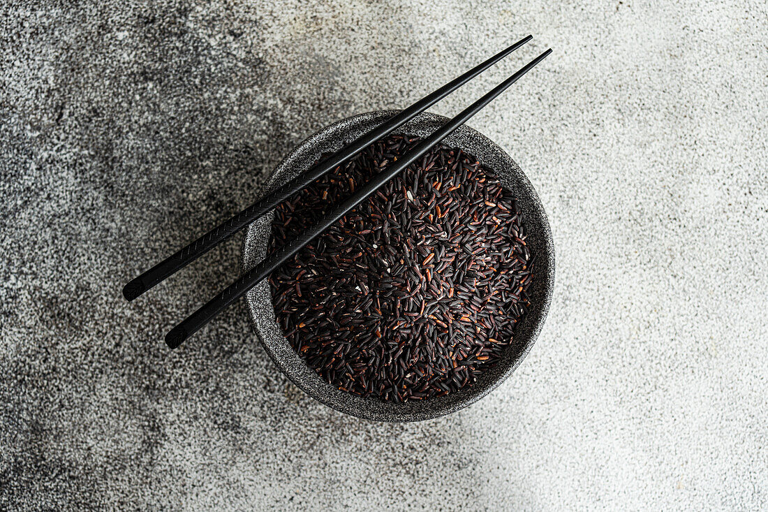 A bowl of black wild rice and chopsticks