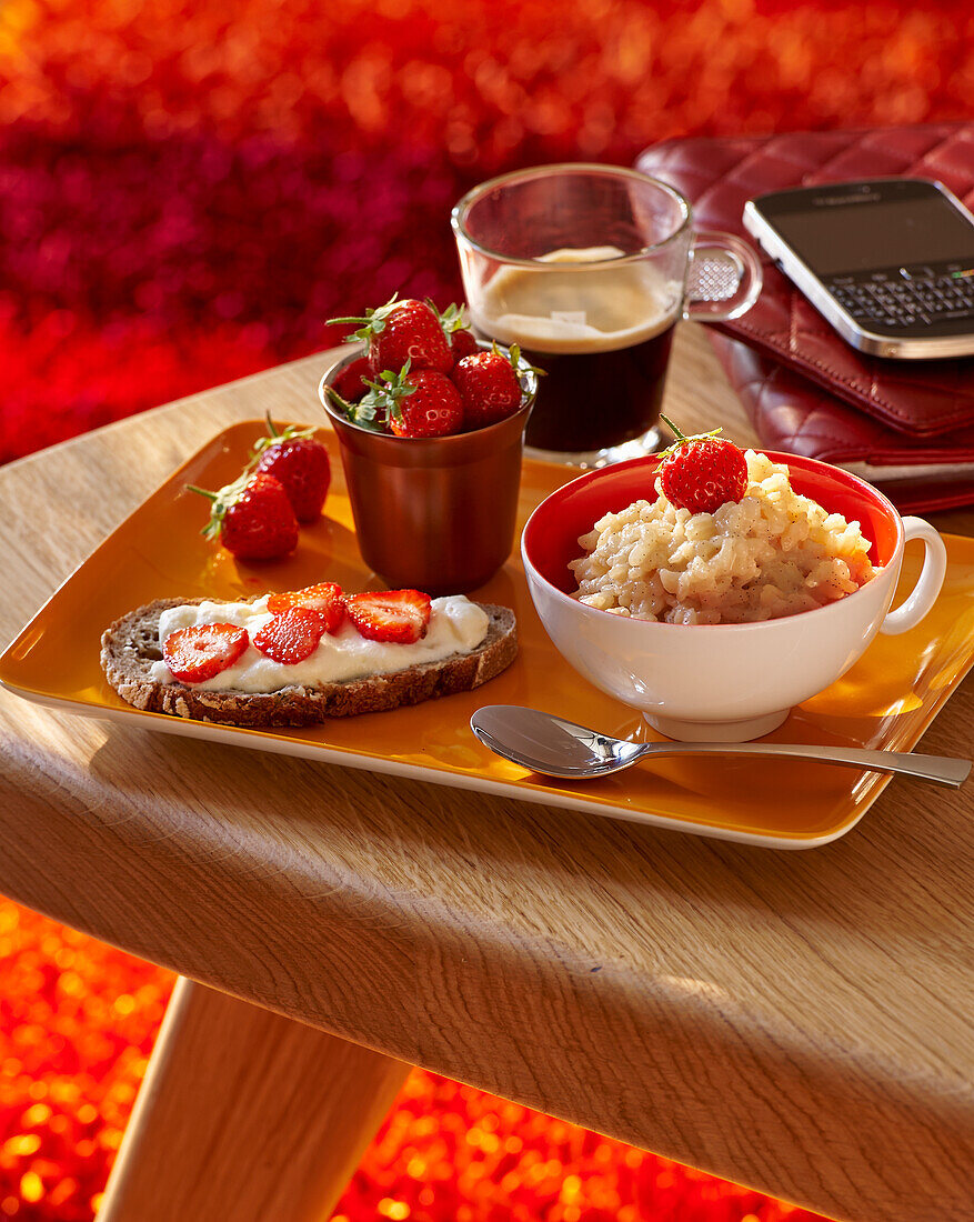 Milchreis, Brot mit Frischkäse und Erdbeeren und Kaffee zum Frühstück