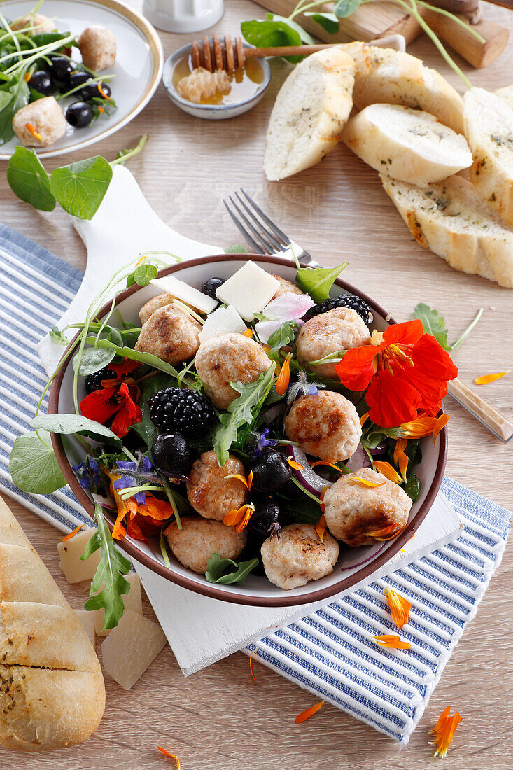Salat mit Fleischbällchen, Brombeeren und essbaren Blüten