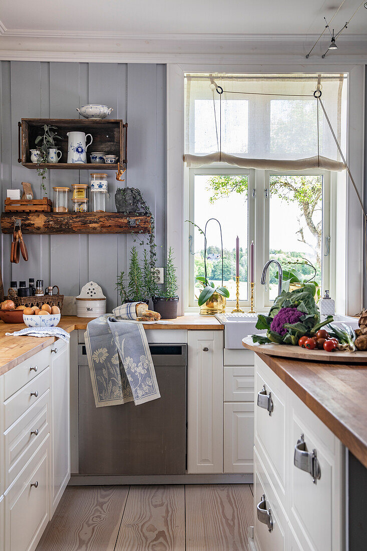 Country-style kitchen with pots of herbs and vegetables on a wooden board