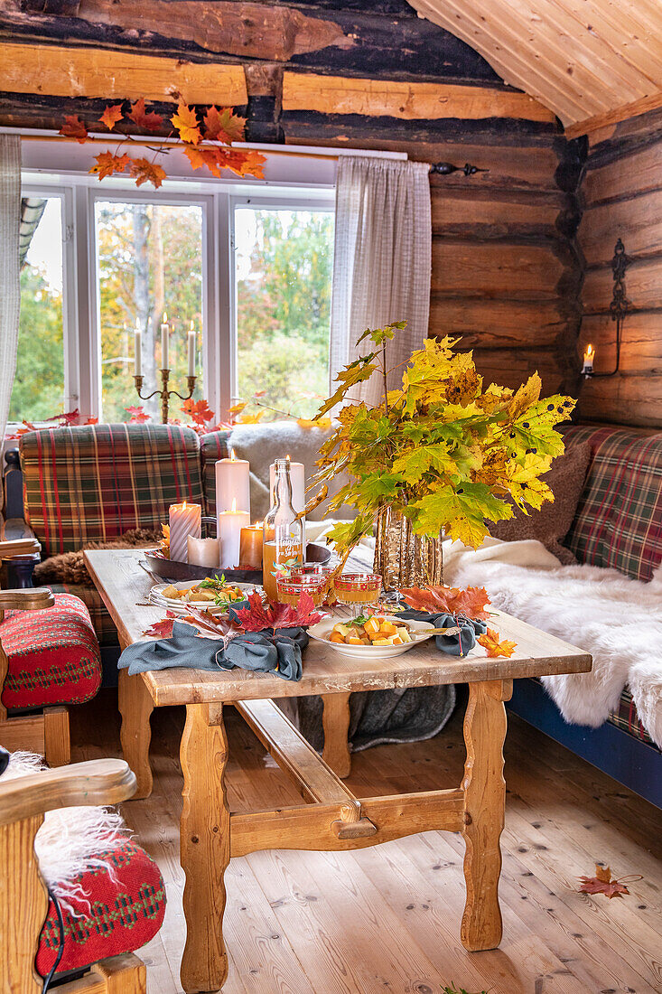 Gedeckter Tisch mit herbstlicher Dekoration im rustikalen Blockhaus