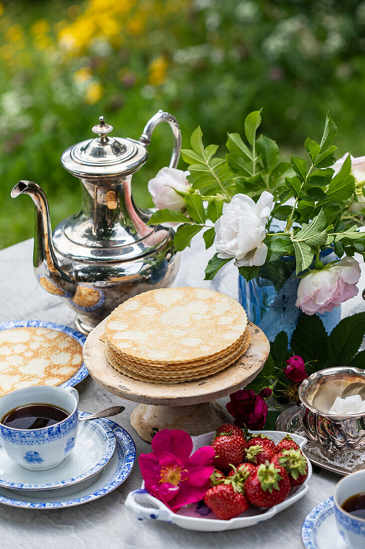 Frühstück im Garten mit Pfannkuchen, Erdbeeren und Kaffee