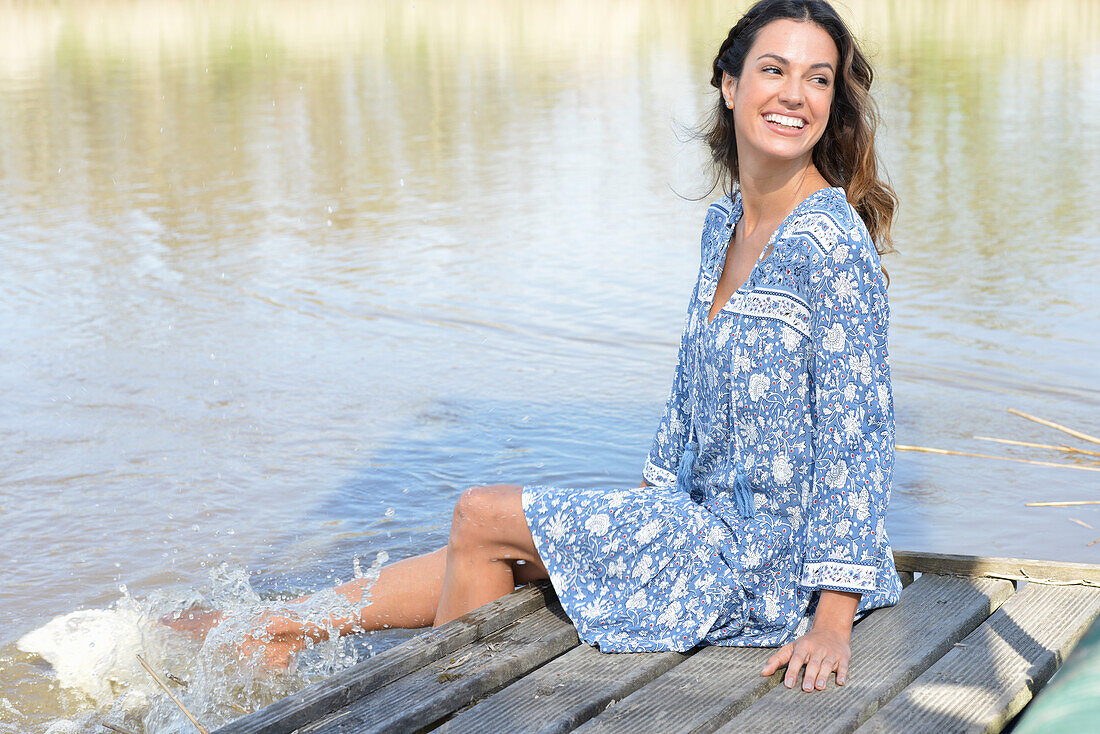 Brunette woman sitting on a wooden pier by the lake