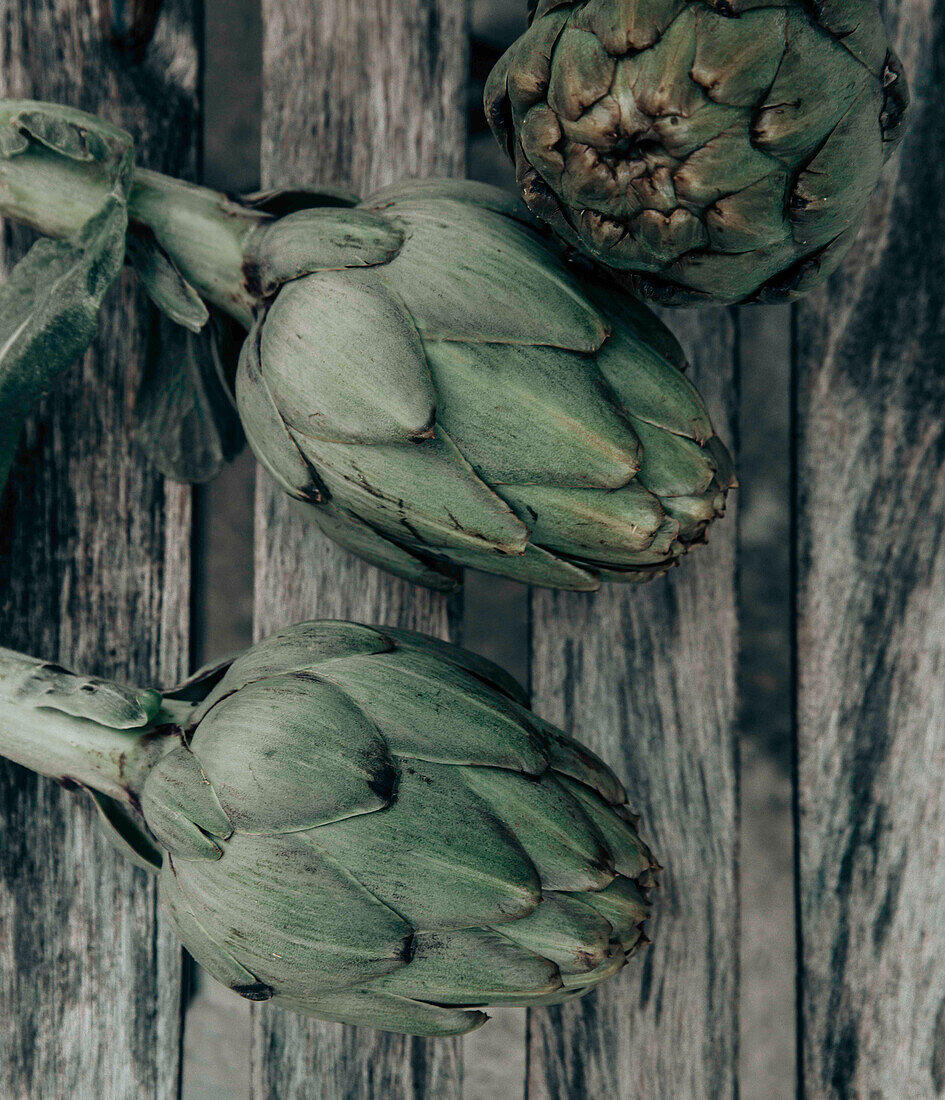 Three artichokes on a wooden background