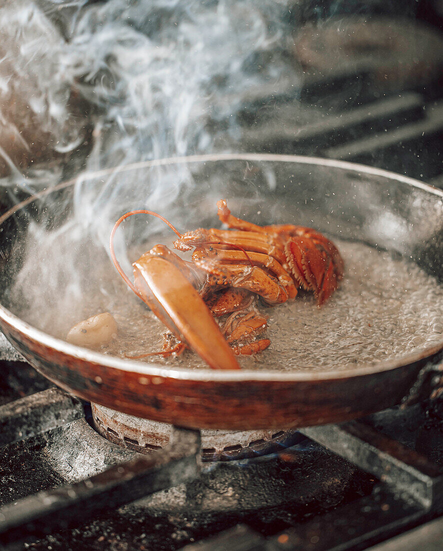Steam hovers around the lobster in the frying pan