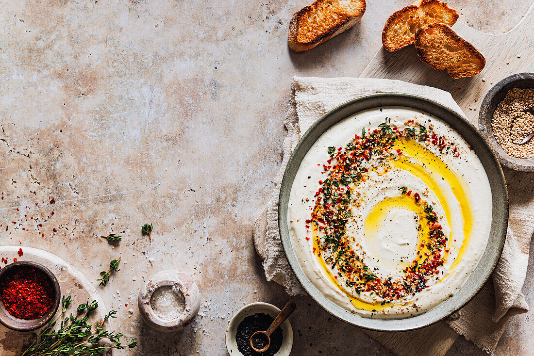 Dip aus Feta-Käse und Joghurt mit Topping aus Olivenöl, Chili, Sesam und Thymian