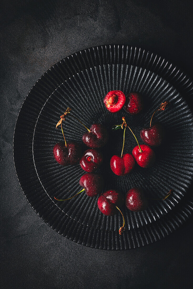Frische rote Kirschen auf schwarzen Tellern