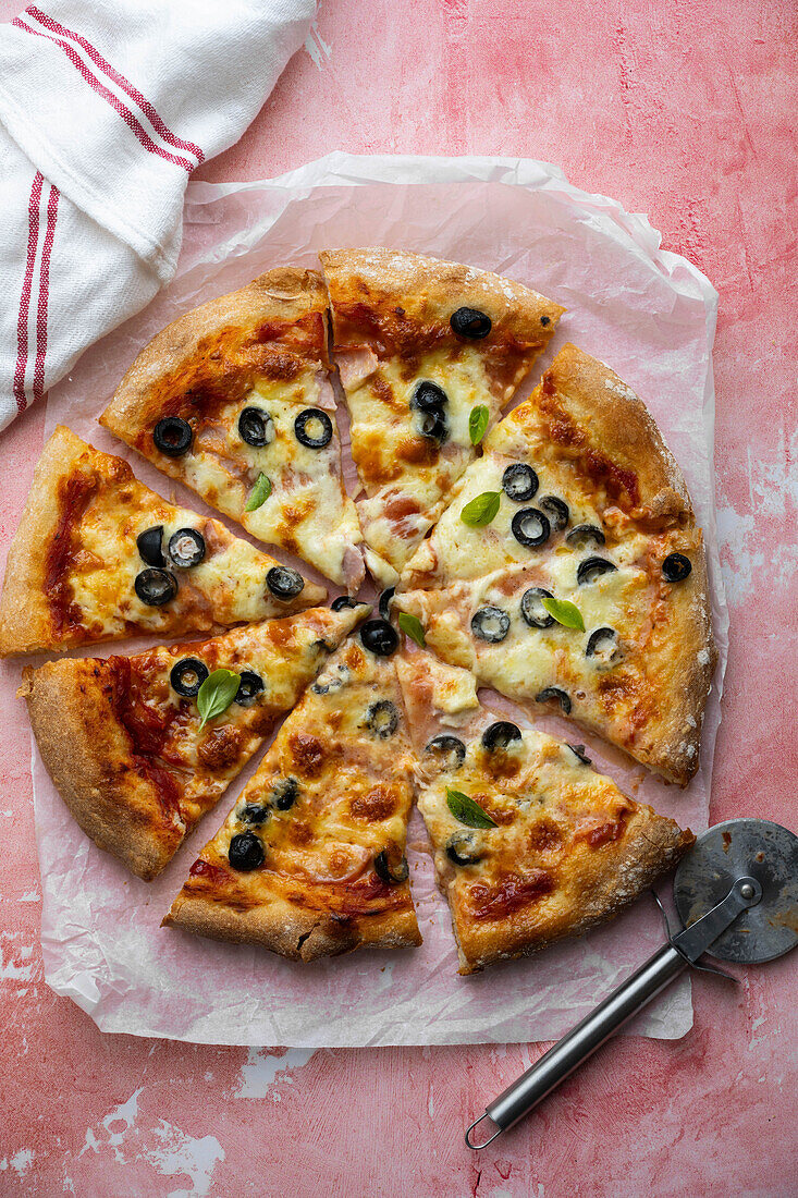 Selbstgemachte Sauerteigpizza mit Schinken und schwarzen Oliven