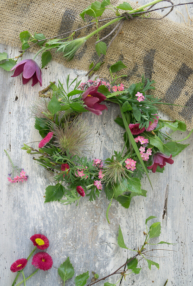 Blumenkranz aus Küchenschelle (Pulsatilla), Vergissmeinnicht, Gänseblümchen (Bellis) und Birkenzweigen