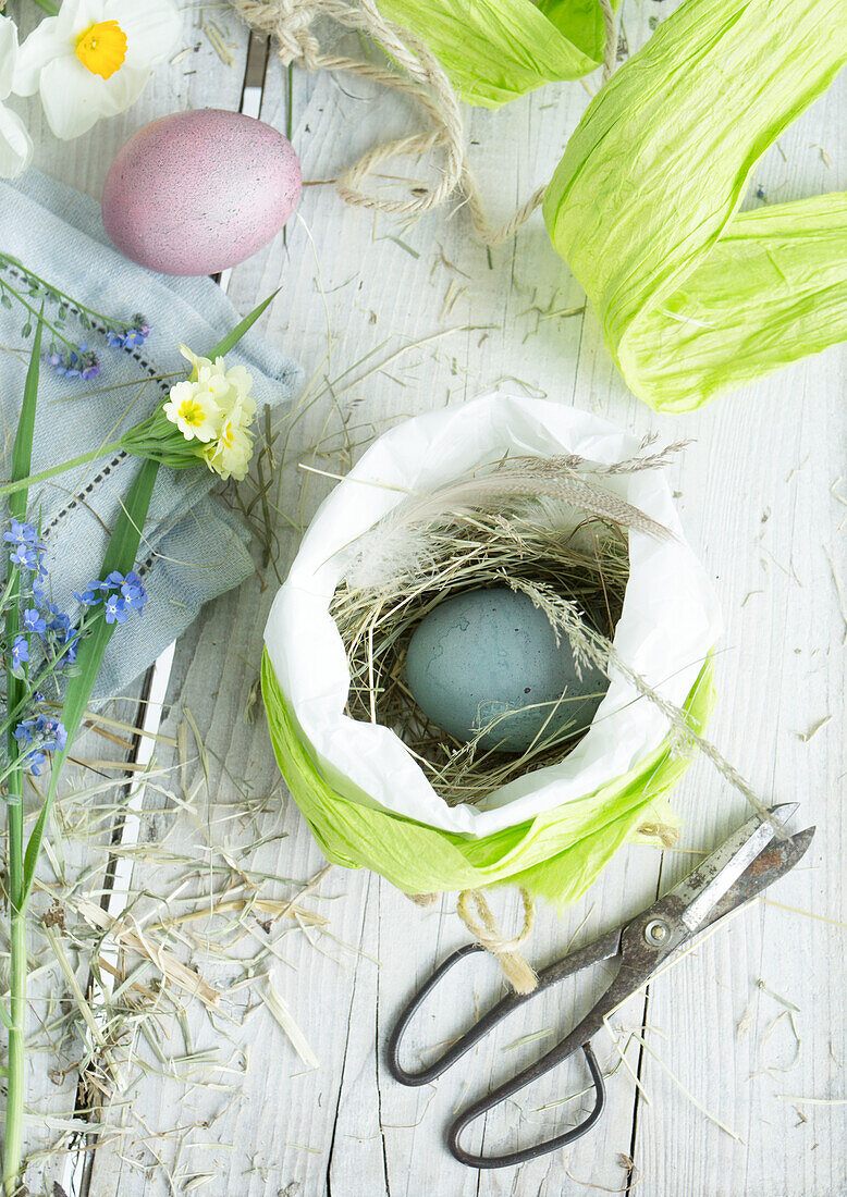 Easter nest in paper bag with Easter egg and hay, handicraft utensils