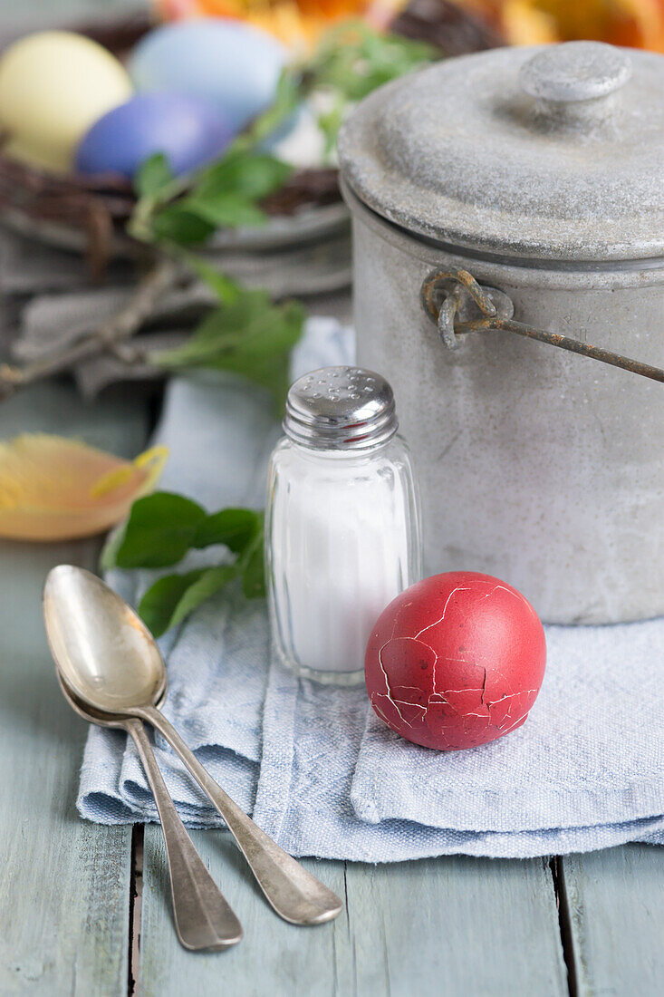 Red Easter egg with broken shell, salt shaker and silver spoons