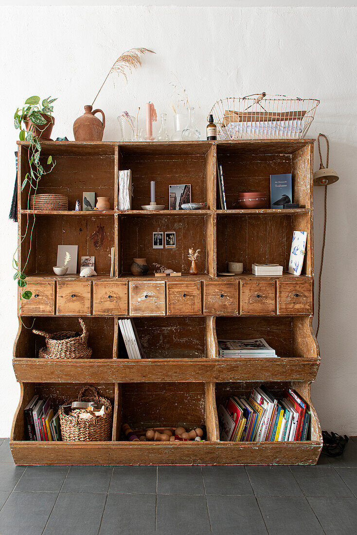 Open vintage wooden cupboard with compartments and drawers, books and decorative objects in vintage style