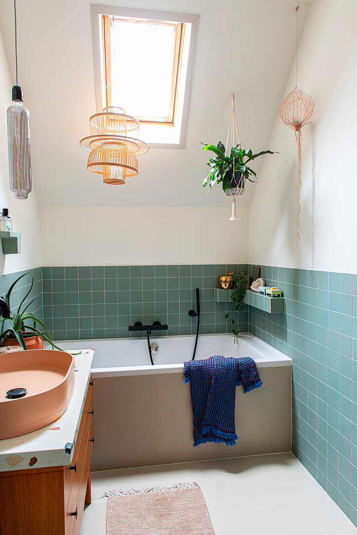 Bathroom with skylight, plants and green tiles in a bathroom