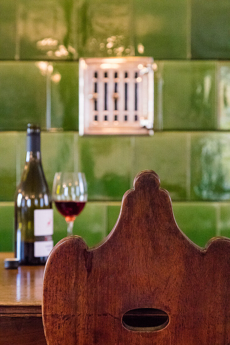Rotwein auf Tisch in Wirtshaus mit grünem Kachelofen