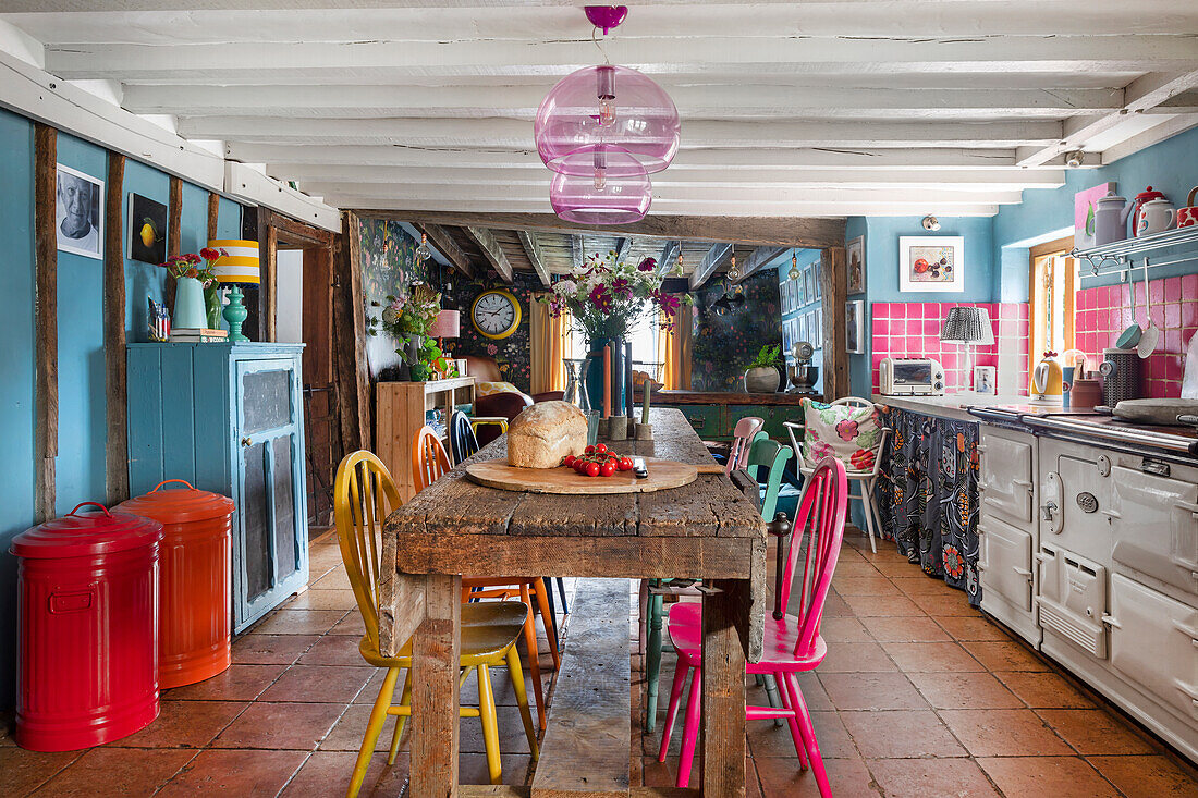 Colourful country-style dining area with rustic wooden table and colourful chairs