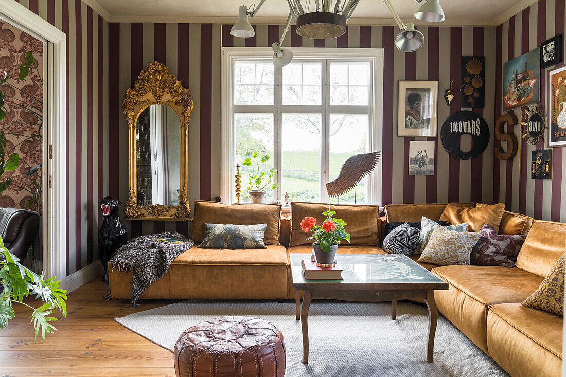 Living room with striped wallpaper, golden corner sofa and antique mirror