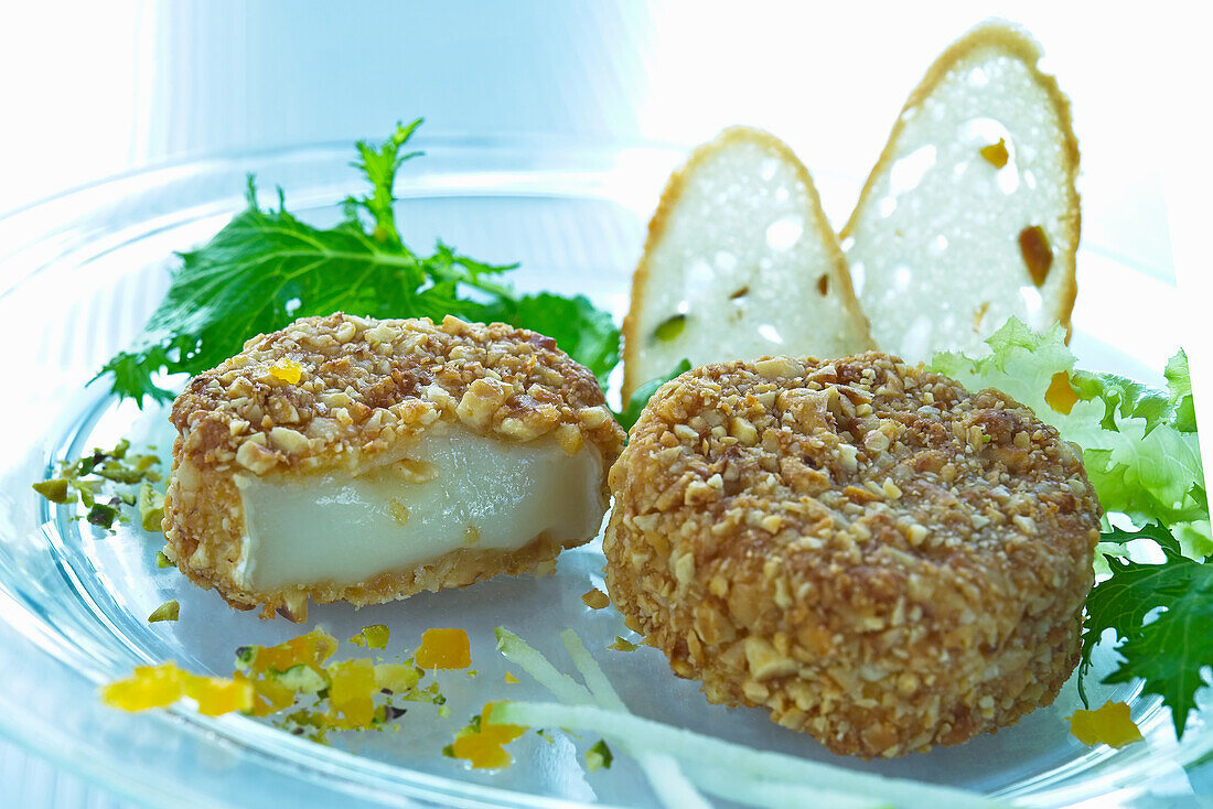 Camembert in breadcrumbs with salad garnish and bread crisps